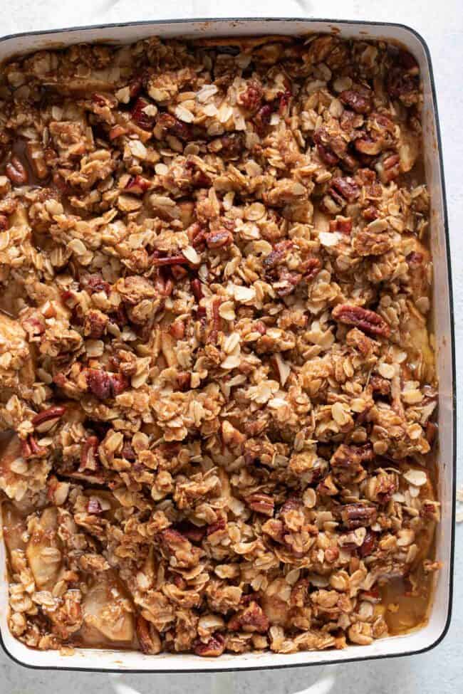 A white baking dish filled with baked apple crisp.