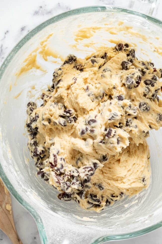 A clear glass mixing bowl filled with cookie dough and chocolate chips.