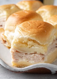 A platter filled with Turkey Sliders made with turkey slices, cheese and Bechamel sauce.