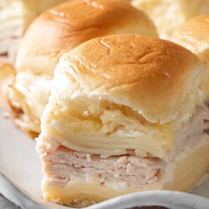 A platter filled with Turkey Sliders made with turkey slices, cheese and Bechamel sauce.
