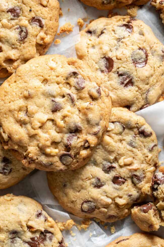 Several chocolate chip cookies scattered on parchment paper.