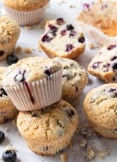 Several blueberry muffins scattered on a marble countertop.