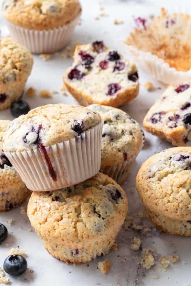 Several blueberry muffins scattered on a marble counter.