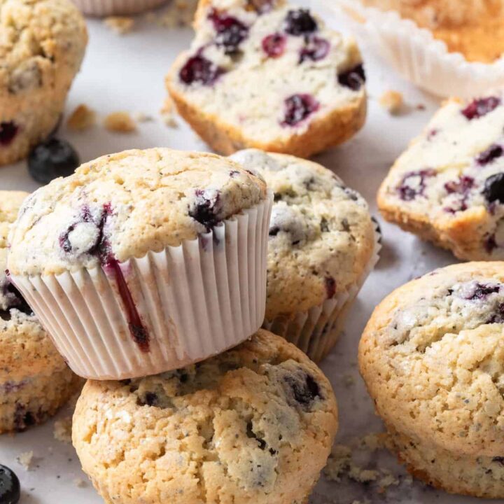 Several blueberry muffins scattered on a marble countertop.