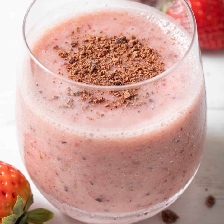 A clear drinking glass filled with Strawberry Cacao Smoothie.