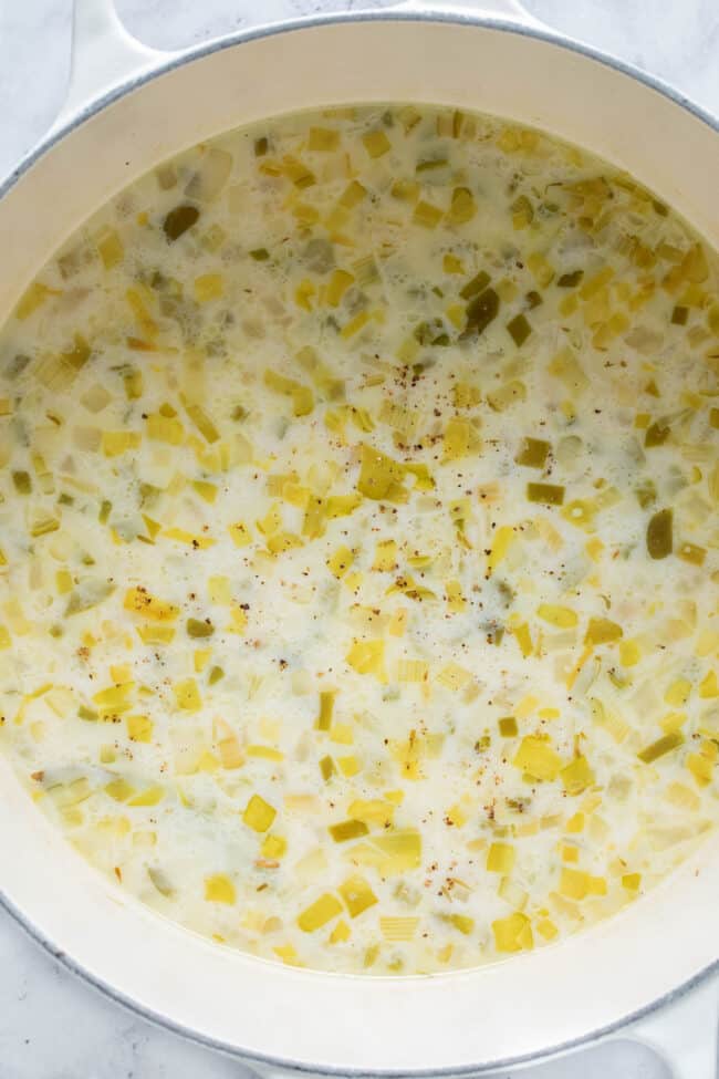 A large white pot filled with creamy New England clam chowder.
