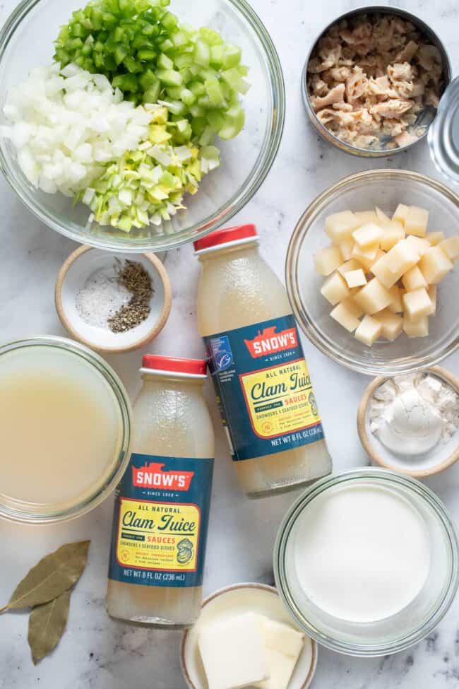 Clear glass bowls filled with chopped vegetables, cream, clam juice, flour, butter and seasoning.