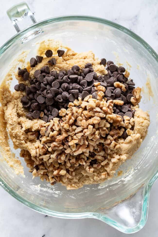 A glass mixing bowl filled with chocolate chip cookie dough.
