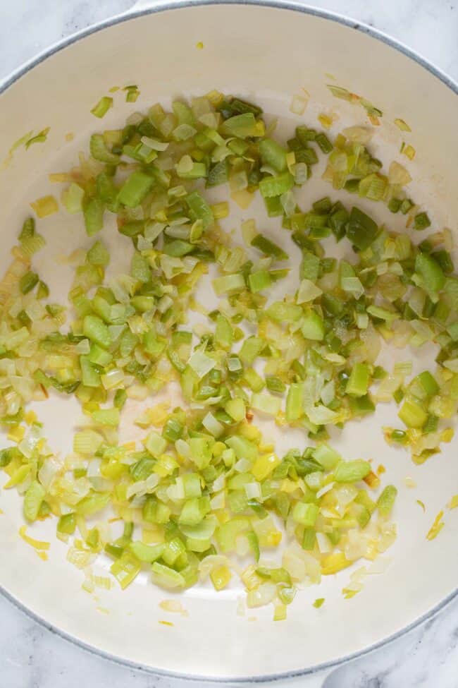 A large white pot filled with sauteed chopped vegetables.