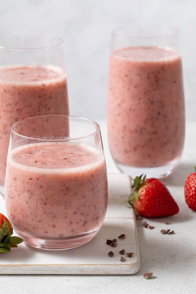 Three clear glasses filled with blended fruit and oat milk.