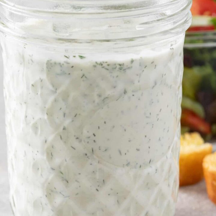 A clear glass mason jar filled with Vegan Ranch Dressing.