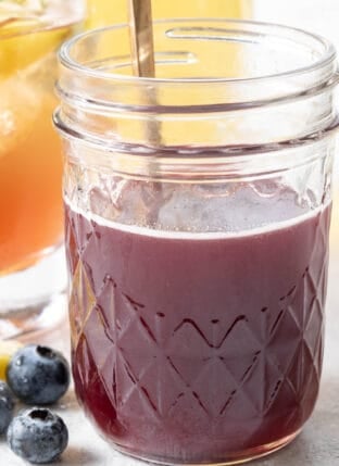 A clear glass mason jar filled with Blueberry Simple Syrup.