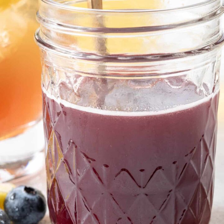 A clear glass mason jar filled with Blueberry Simple Syrup.