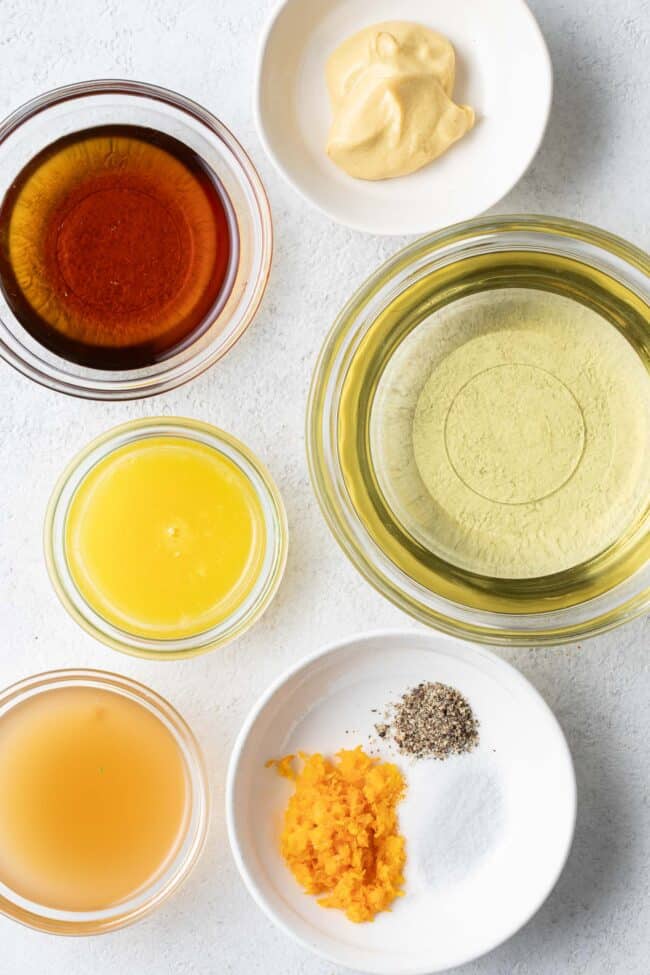 Clear glass mixing bowls filled with olive oil, apple cider vinegar and maple syrup.