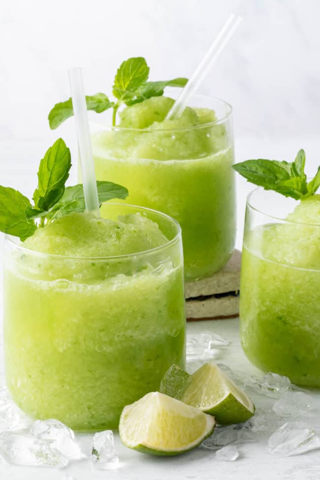 Three clear glasses filled with frozen fruit and ice.