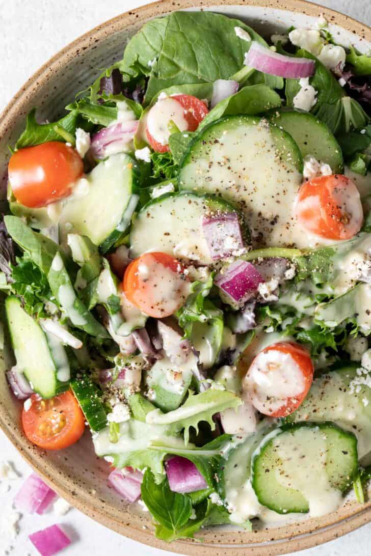 A tan colored bowl filled with salad.