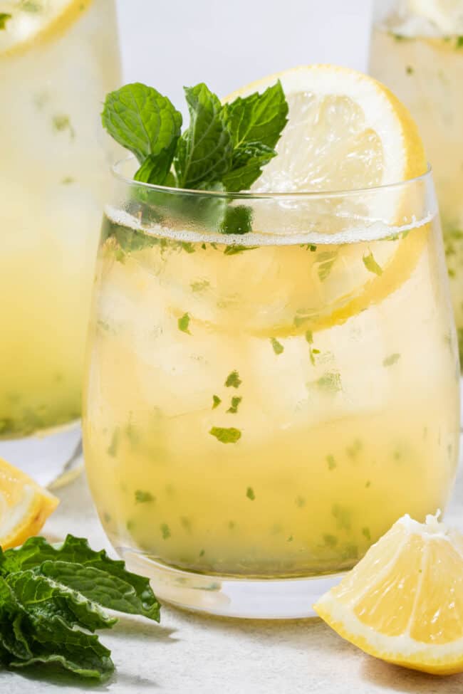 A clear glass filled with Iced Lemon Mint Green Tea.