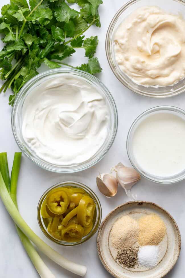 Clear glass measuring bowls filled with mayonnaise, sour cream and buttermilk.