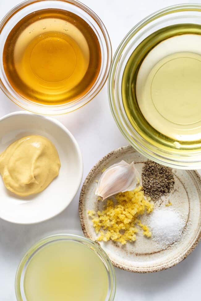 Three clear glass bowls filled with liquids and one small bowl filled with mustard and another filled with spices.