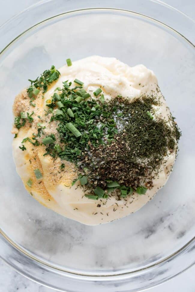 A white mixing bowl filled with mayonnaise and dried seasoning.