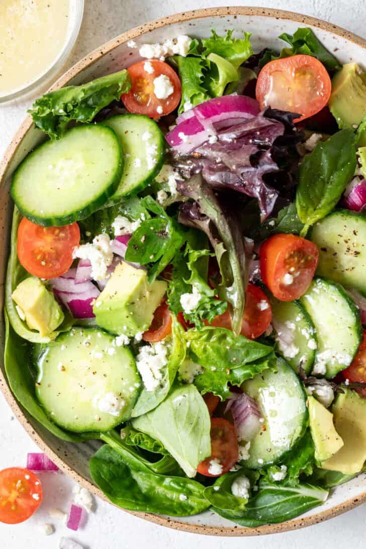 A tan colored bowl filled with spring mix salad.