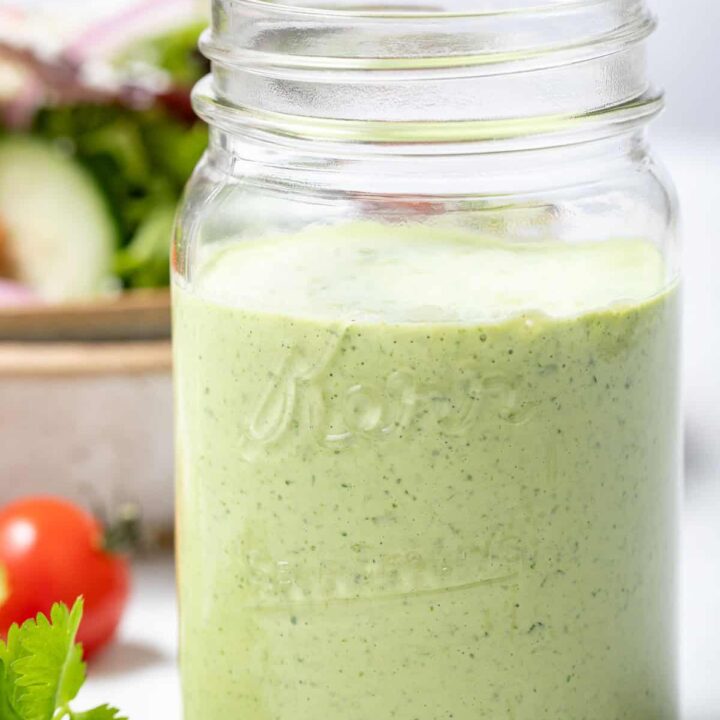 A clear mason jar filled with Creamy Cilantro Dressing.