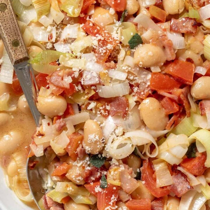 A white skilled filled with canned Butter Beans. A serving spoon rests in the skillet.