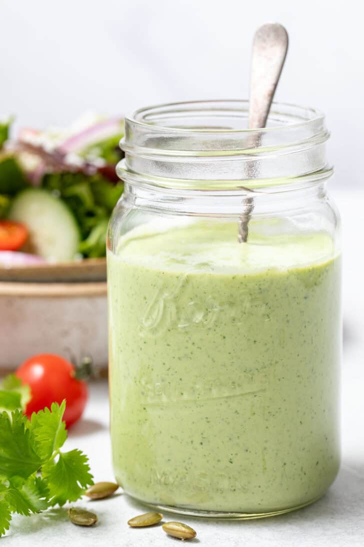 A clear mason jar filled with creamy cilantro dressing.