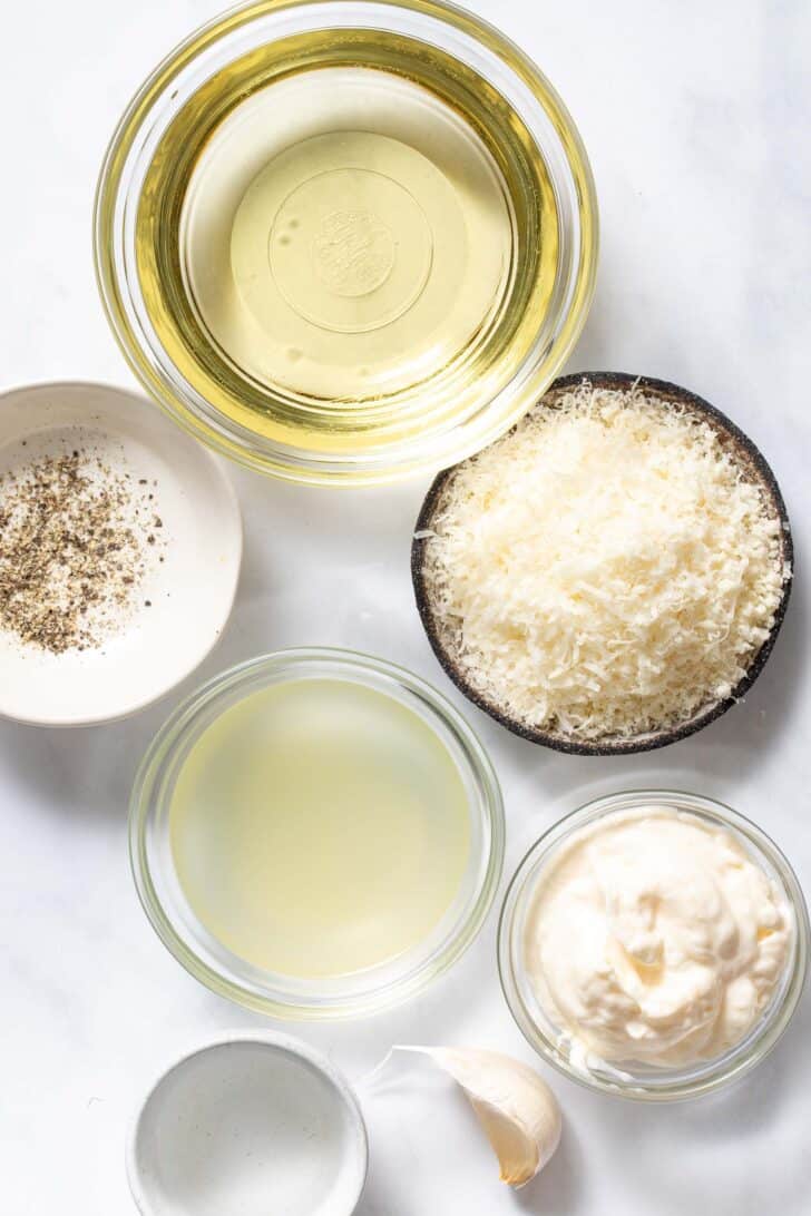 Four small glass bowls filled with lemon juice, olive oil, mayonnaise and Parmesan cheese.