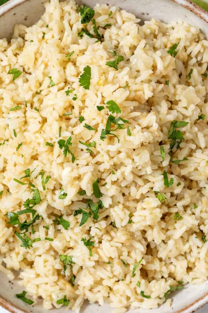 A tan colored bowl filled with Mexican green rice.
