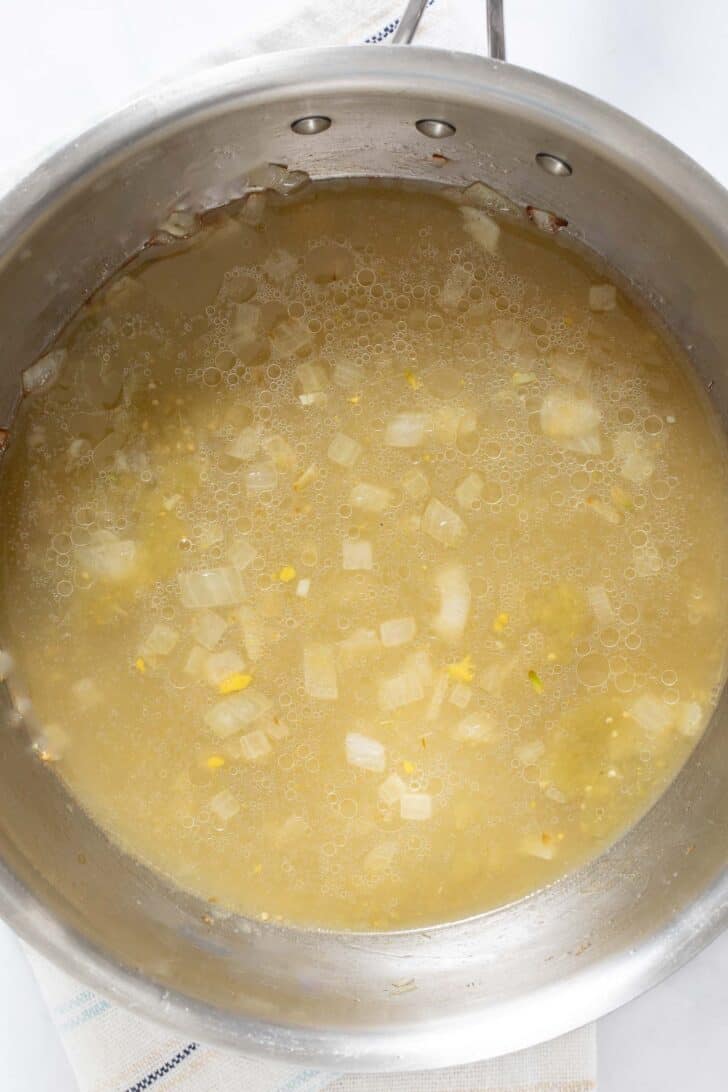 A pot filled with cooked onion and broth.