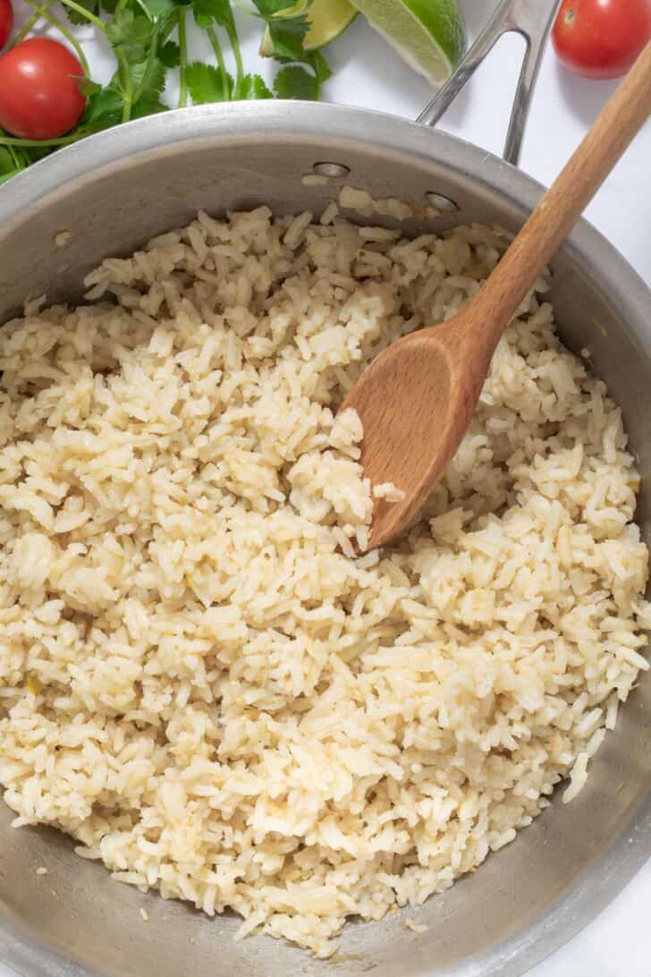 A pot filled with Mexican green rice. A wooden spoon rests in the pot.