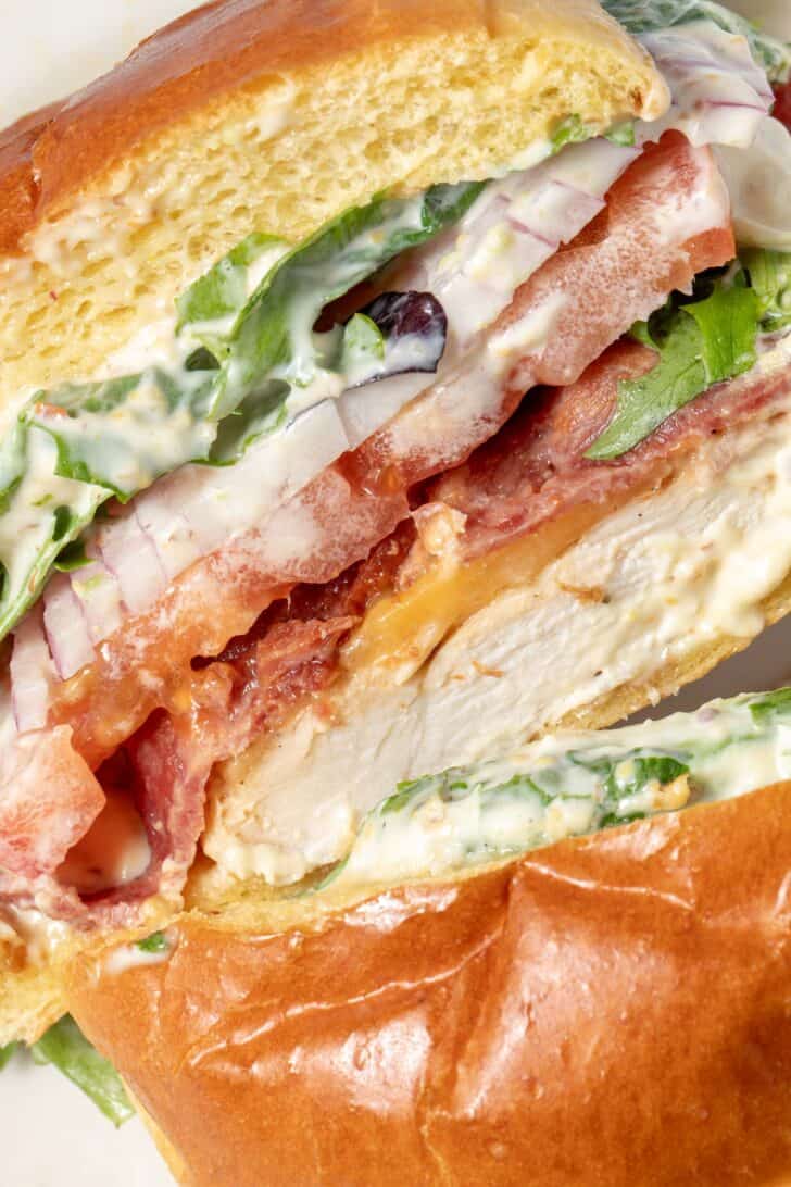 A sandwich sliced in half to see the lettuce, onion, tomato and bacon.
