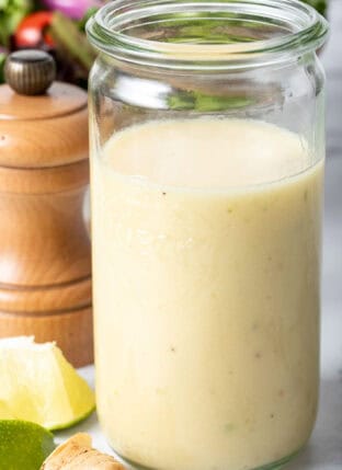 A clear glass mason jar filled with Lime Ginger Vinaigrette.