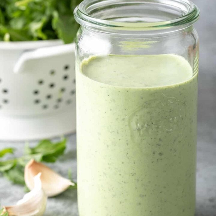 A clear glass mason jar filled with homemade Green Goddess Dressing.