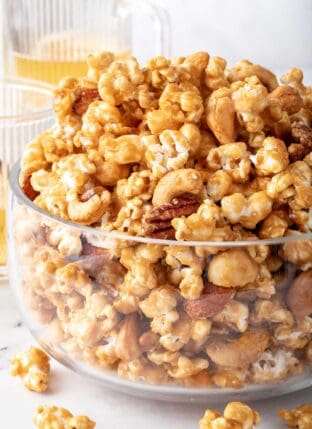 A clear glass bowl filled with Caramel Popcorn.