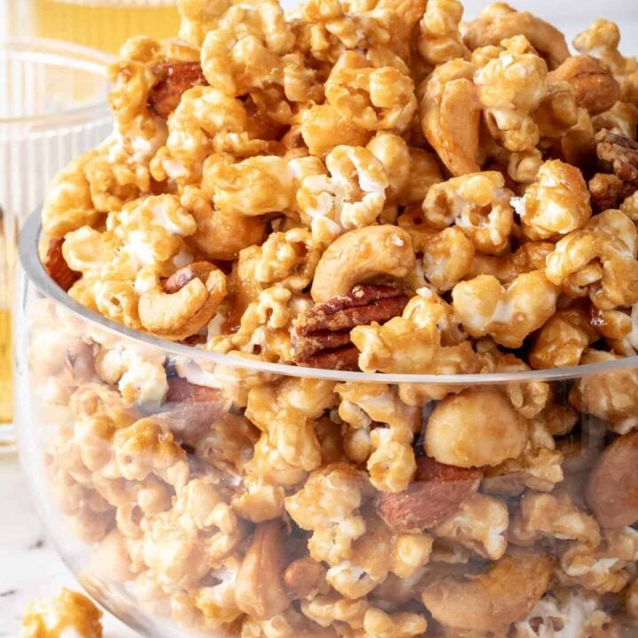 A clear glass bowl filled with Caramel Popcorn.