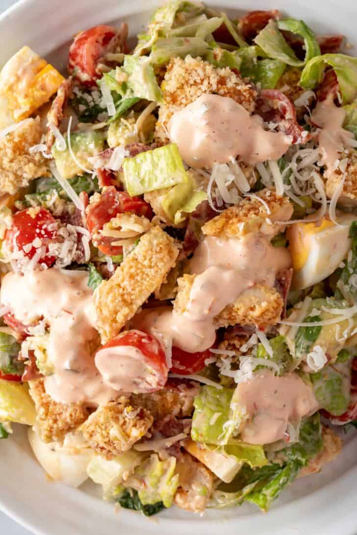 A white bowl filled with Crispy Chicken Cobb Salad.