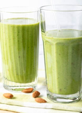 Two drinking glasses filled with kale smoothie.