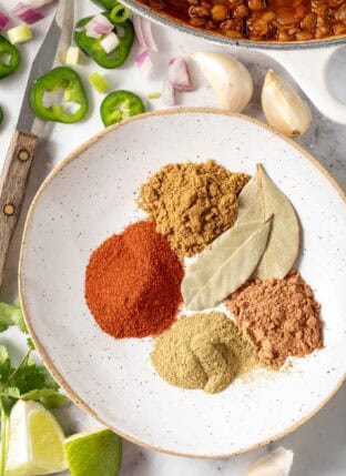 A small dish with scoops of spices to make homemade chili seasoning recipe.