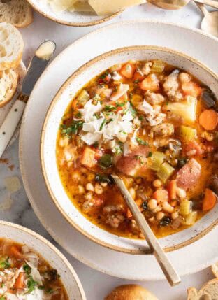 A white bowl filled with Sausage Kale White Bean Soup.
