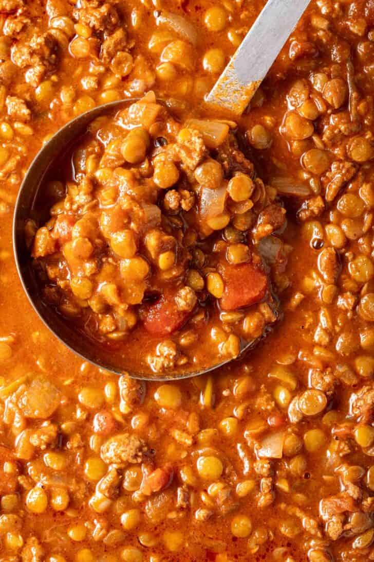 A pot filled with turkey lentil chili. A metl ladle rests in the pot.