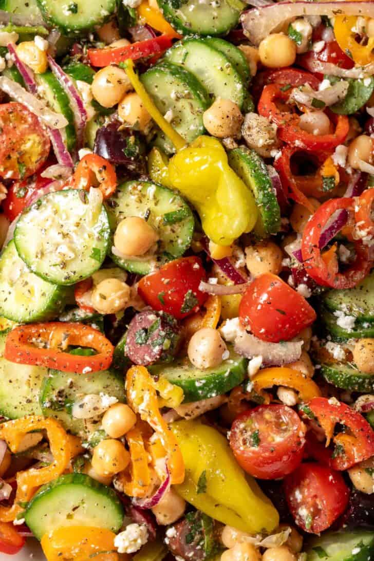 A bowl filled with tossed Greek Chickpea Salad with cherry tomatoes, Kalamata olives, fresh mint and feta cheese.
