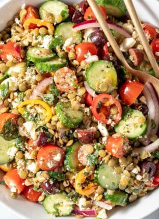 A white bowl filled with Greek Lentil Salad.