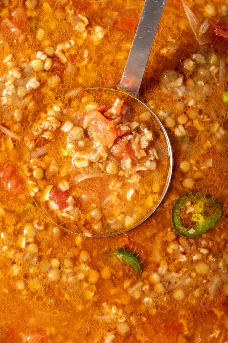 A pot of lentil brown rice soup. A ladle rests in the pot.