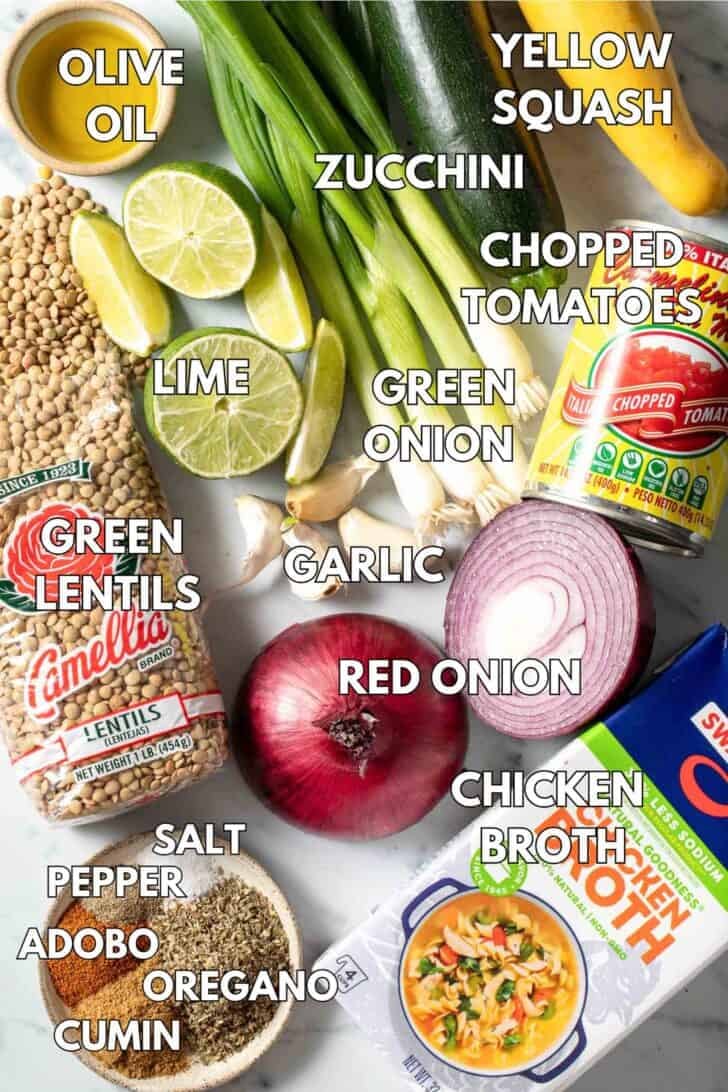 Ingredients for a legume brothy stew (canned tomatoes, chicken broth, zucchini, onion, spices, limes and legumes).