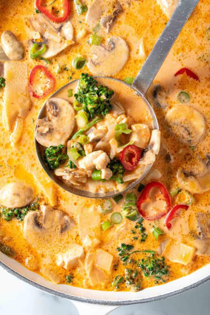 A white Dutch oven filled with a creamy stew with vegetables.
