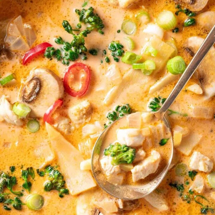 A bowl filled with Tom Kha Gai Thai Coconut Chicken Soup with curry paste.