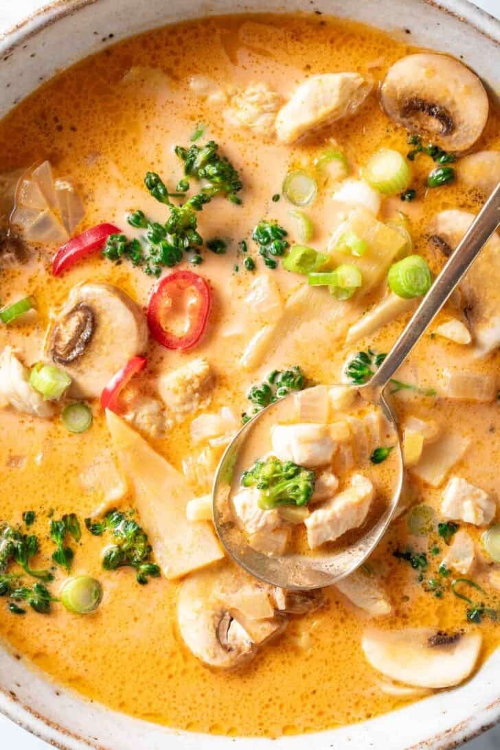 A bowl filled with Tom Kha Gai Thai Coconut Chicken Soup with curry paste. 