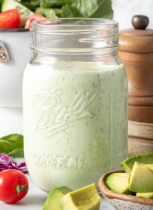 A clear mason jar filled with Avocado Ranch Dressing.